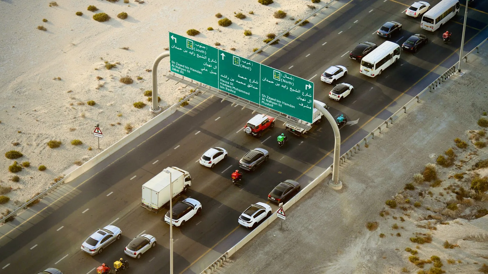 UAE highway traffic beneath bilingual directional signs